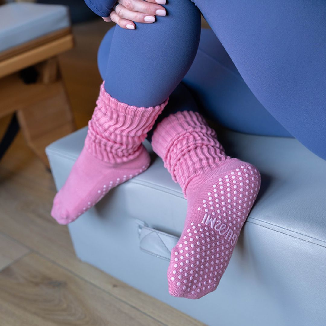 A lady with legs crossed wearing GUMMI pink grip socks.