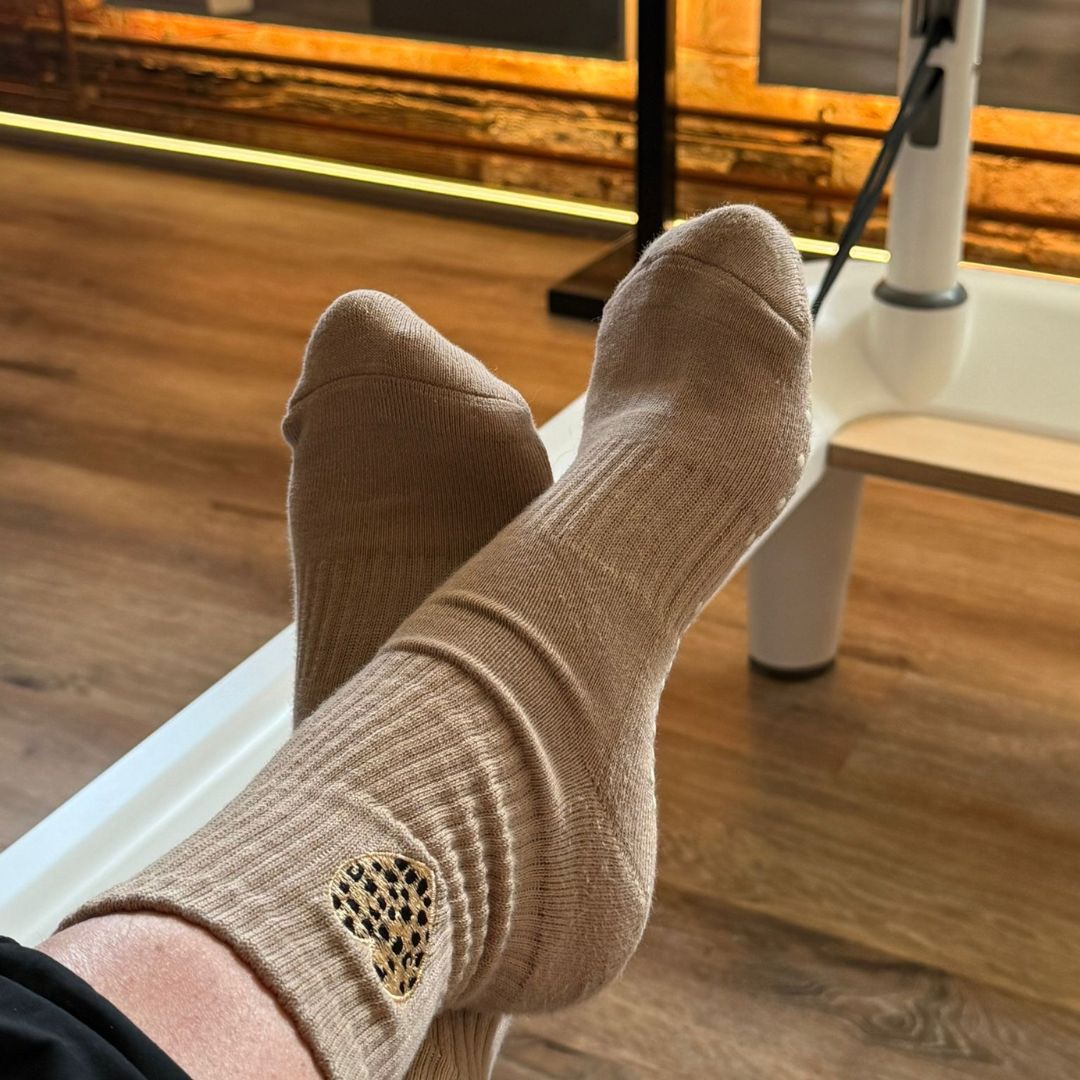 Beige pilates socks with a heart design on a reformer bed.