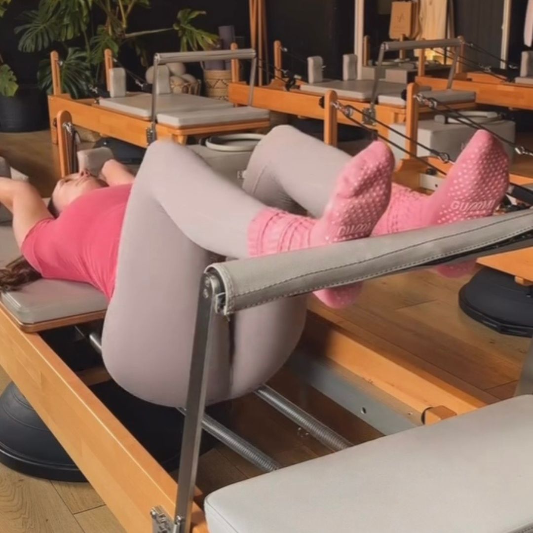 Person using a Pilates reformer machine in a studio setting